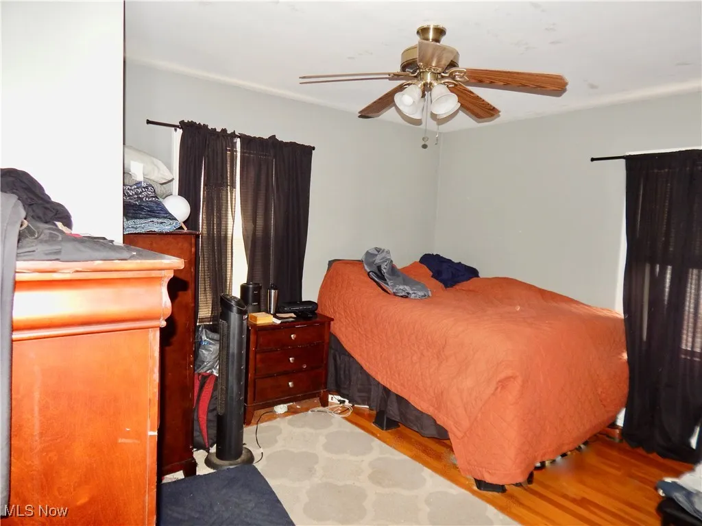 Upstairs unit Bedroom with ceiling fan and hardwood floors