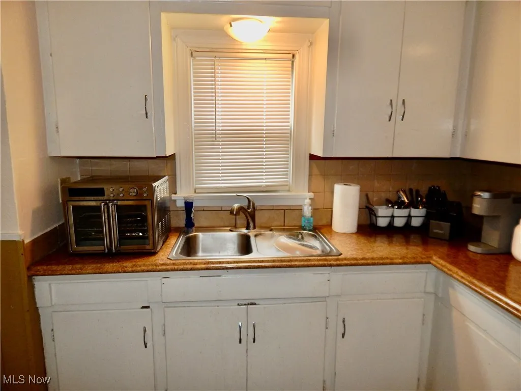 Kitchen with white cabinets, a sink, and decorative backsplash