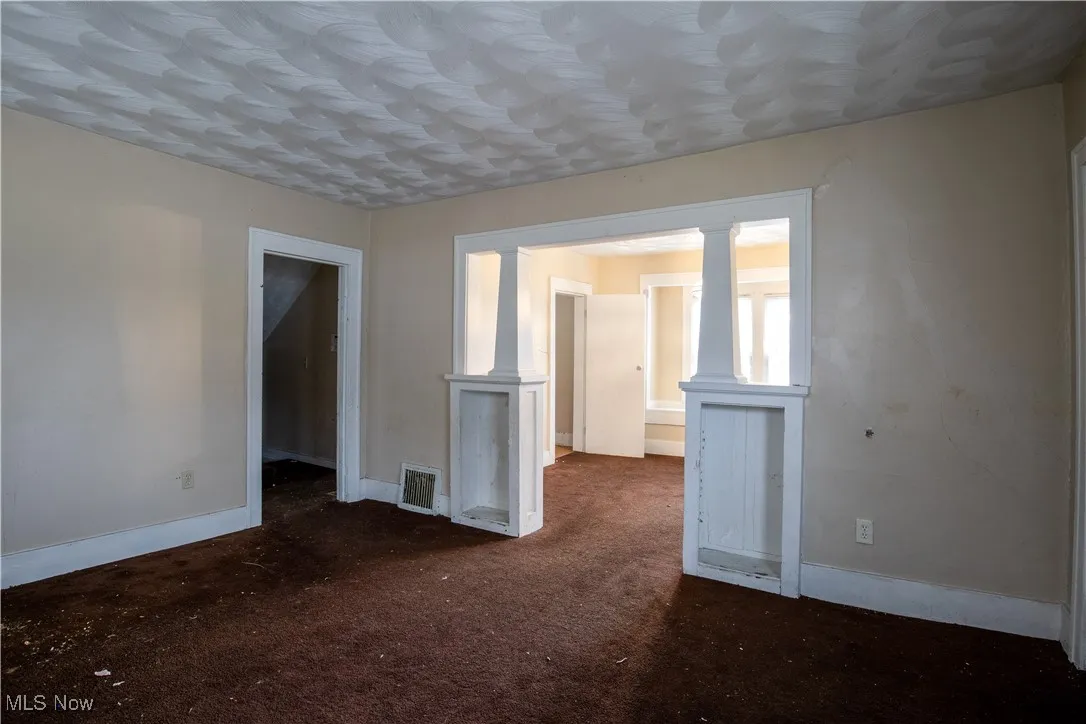 Spare room with ornate columns, baseboards, and carpet flooring