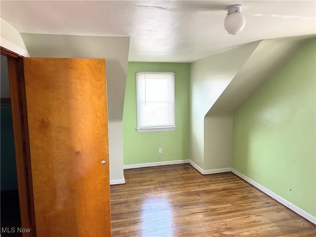 Additional living space featuring lofted ceiling, wood finished floors, and baseboards