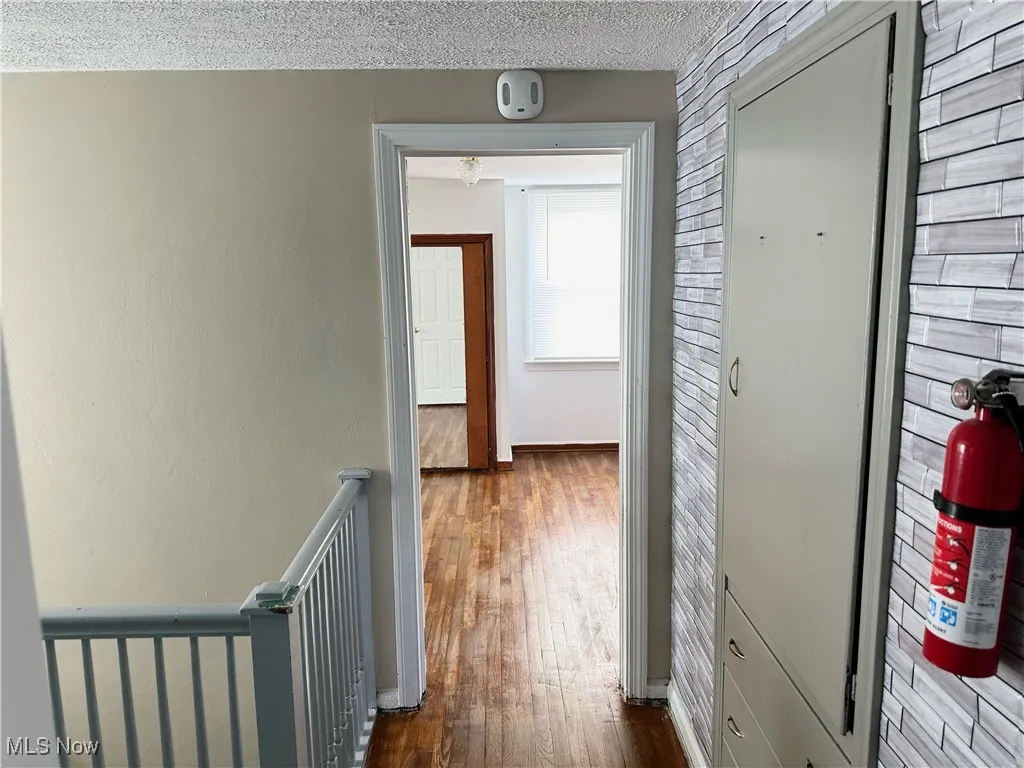 Corridor with a textured ceiling, dark wood-type flooring, and baseboards
