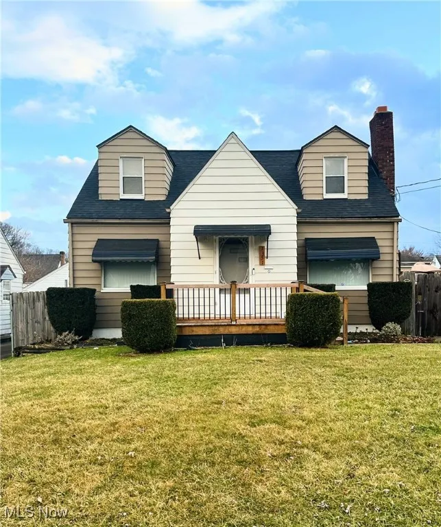 View of front of house with a front yard, roof with shingles, fence, and a chimney