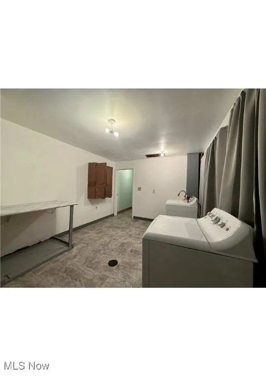 Washroom with washing machine and dryer and baseboards