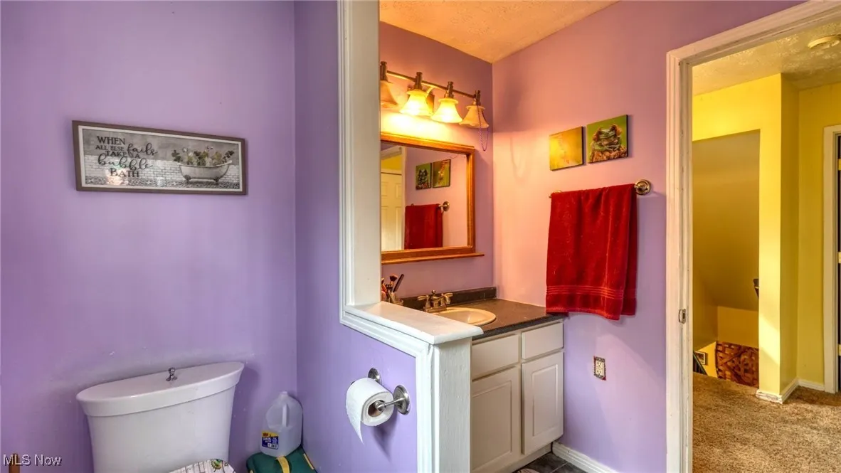Bathroom with toilet, vanity, and baseboards