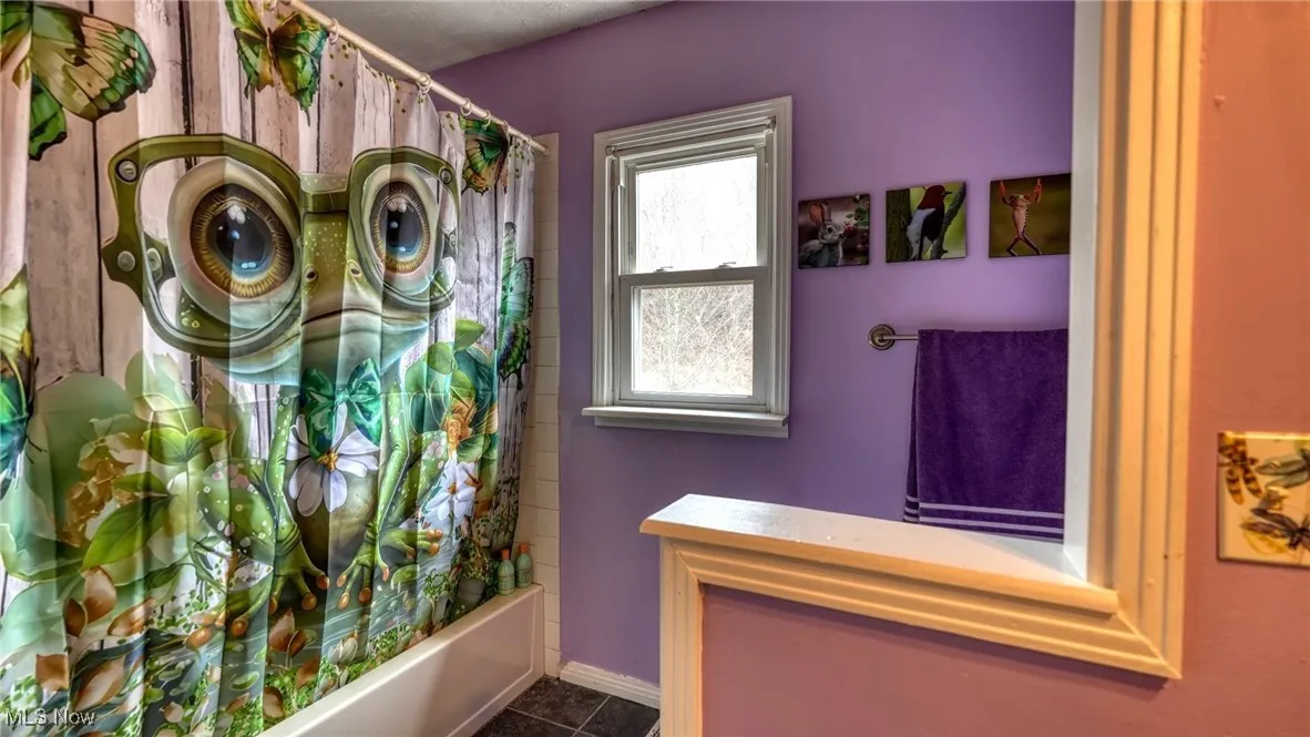 Bathroom featuring shower / bath combo, tile patterned flooring, and baseboards