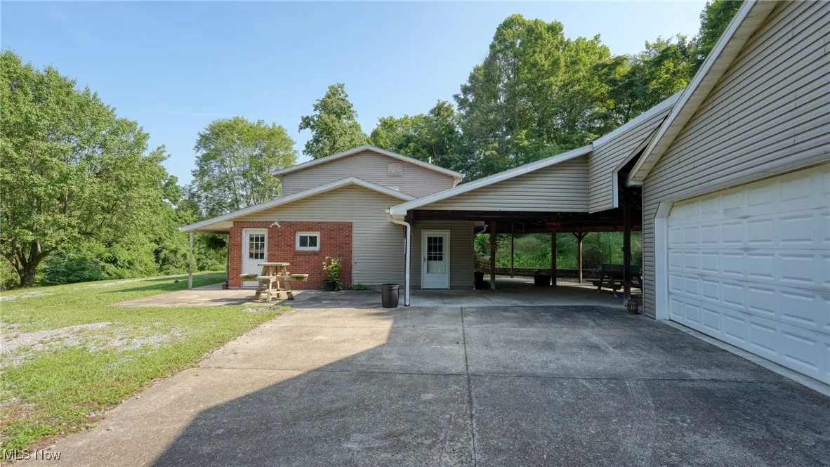 View of front facade with a carport, a front yard, driveway, a garage, and brick siding