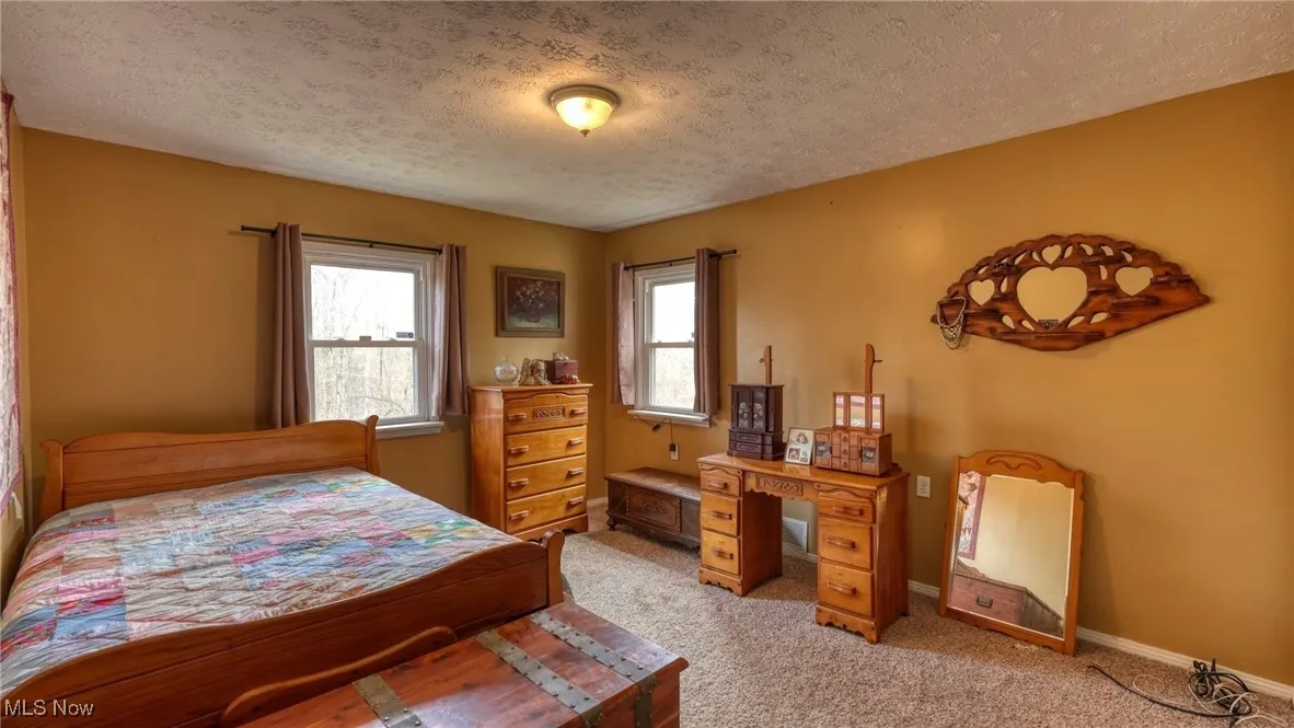 Bedroom with light carpet, baseboards, and a textured ceiling