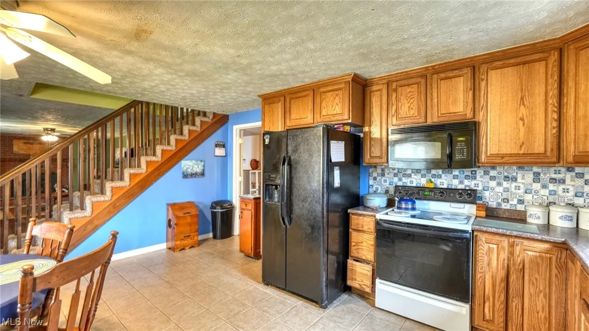 Kitchen with black appliances, tasteful backsplash, a ceiling fan, and brown cabinets