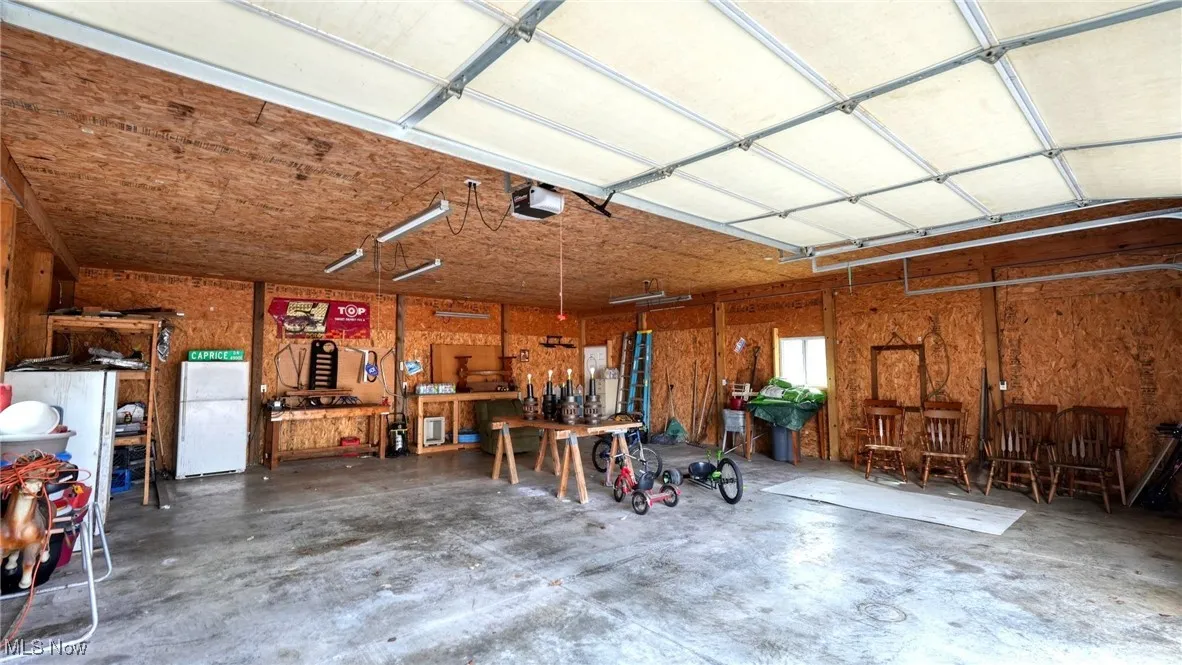 Garage featuring a workshop area, freestanding refrigerator, and a garage door opener