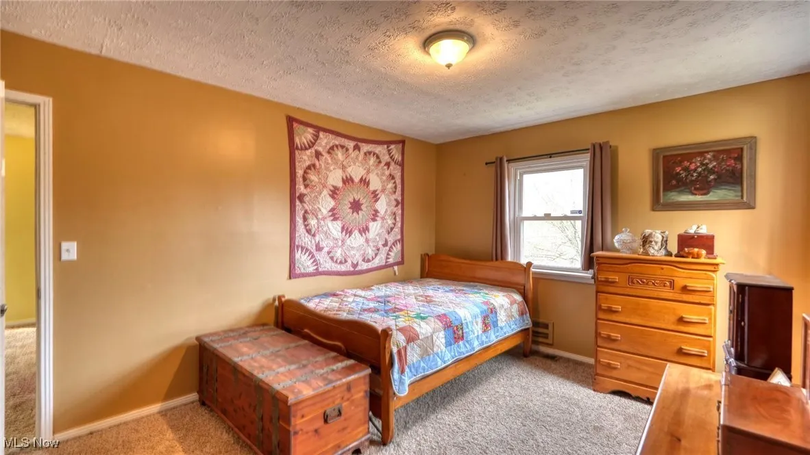 Carpeted bedroom with baseboards and a textured ceiling