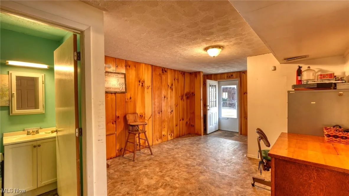 Entry area with wood walls, a textured ceiling, a sink, and tile patterned floors