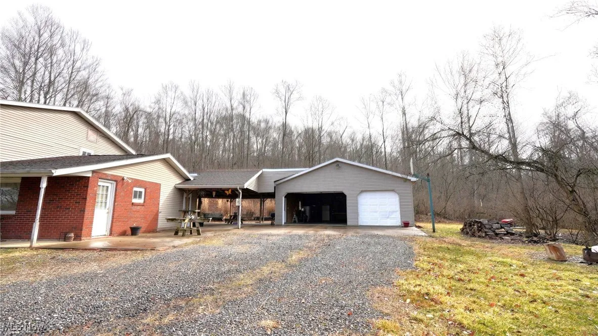 View of side of property with brick & vinyl siding with detached garage and covered patio area