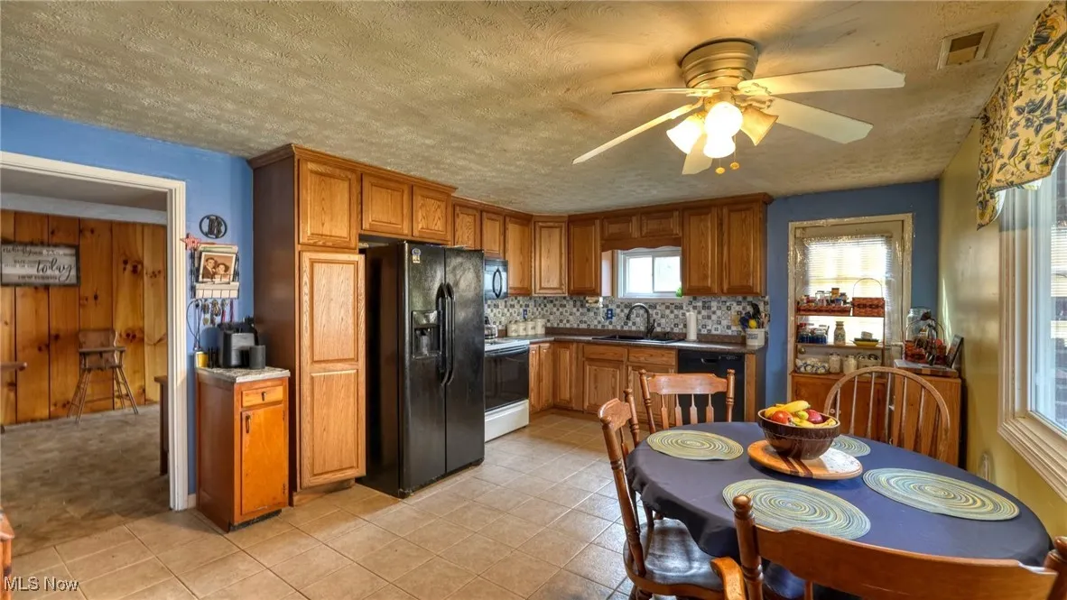 Kitchen with brown cabinets, tasteful backsplash, visible vents, a sink, and black appliances