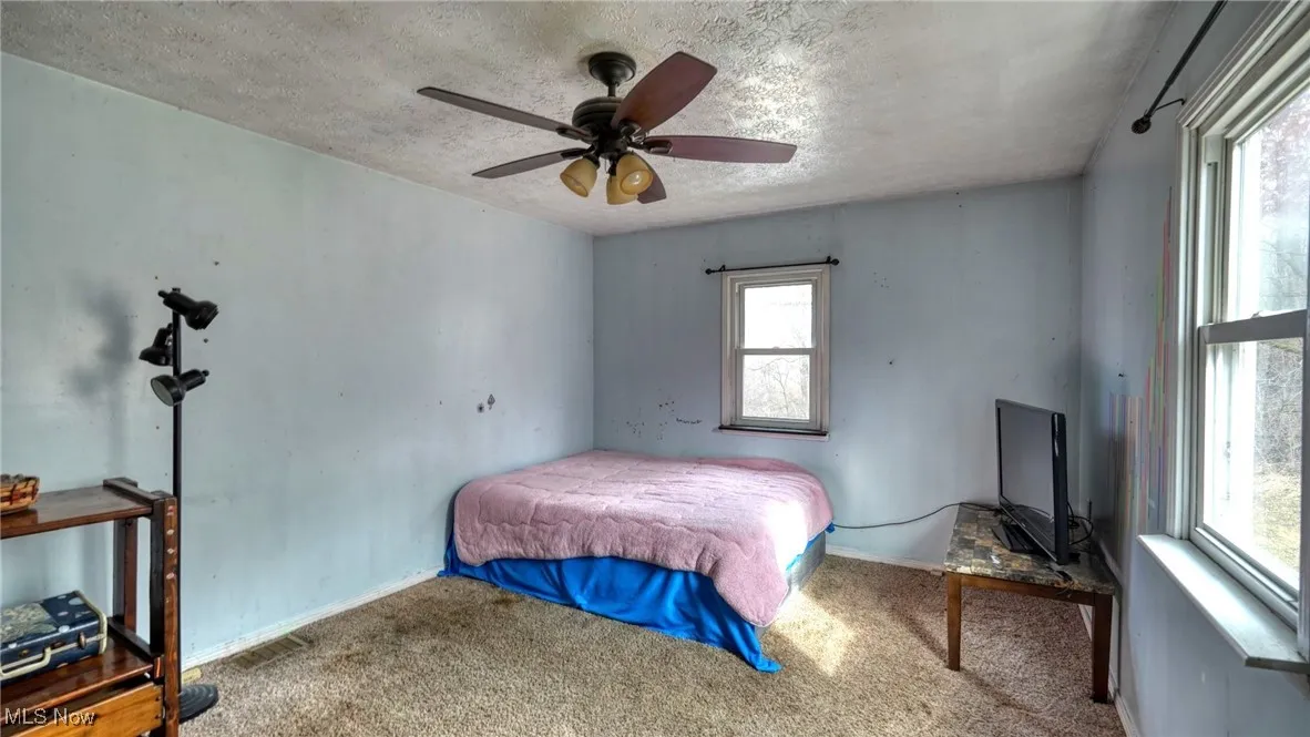 Bedroom with baseboards, a textured ceiling, a ceiling fan, and carpet flooring