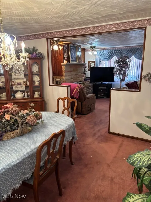 Dining area with carpet and ceiling fan with notable chandelier
