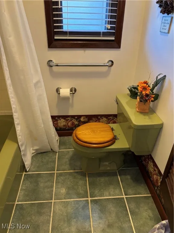 Bathroom featuring toilet, shower / bath combo, and tile patterned floors
