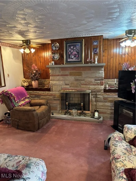 Living room with carpet floors, a fireplace, and ceiling fan