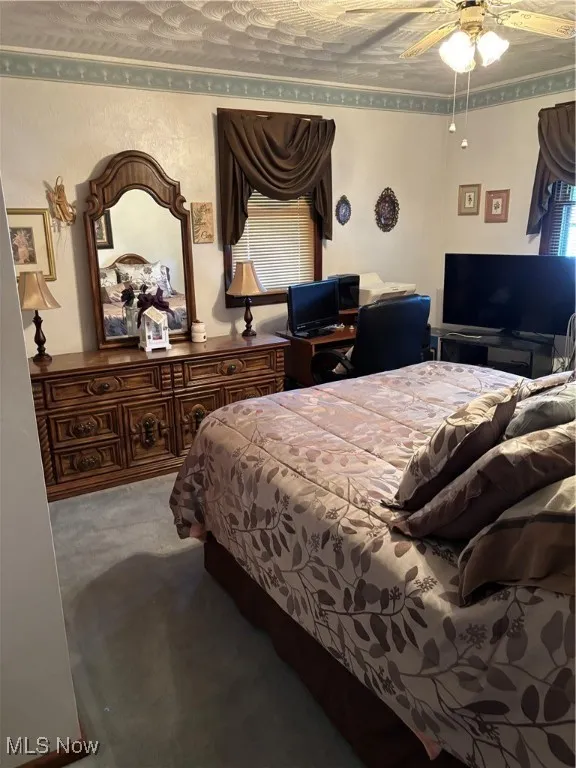 Carpeted bedroom with ornamental molding and ceiling fan