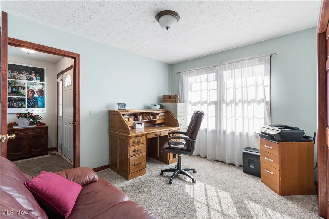 Carpeted office with a textured ceiling and baseboards