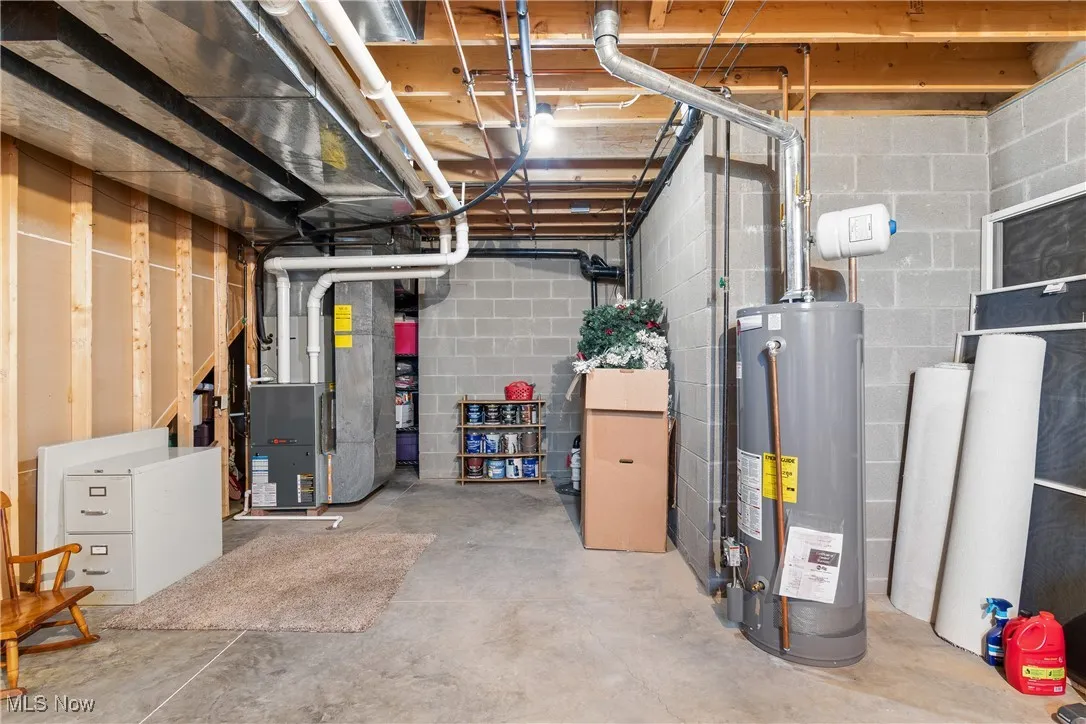 Unfinished below grade area featuring water heater and heating unit