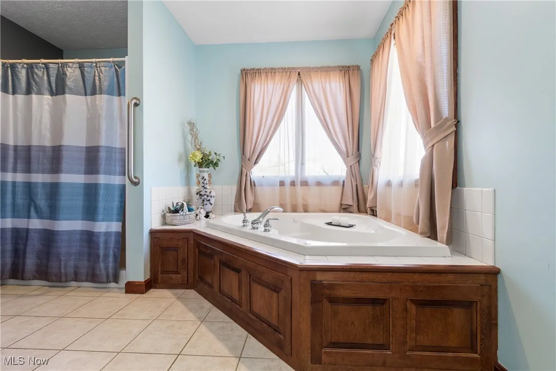 Full bathroom featuring curtained shower, tile patterned flooring, and a bath