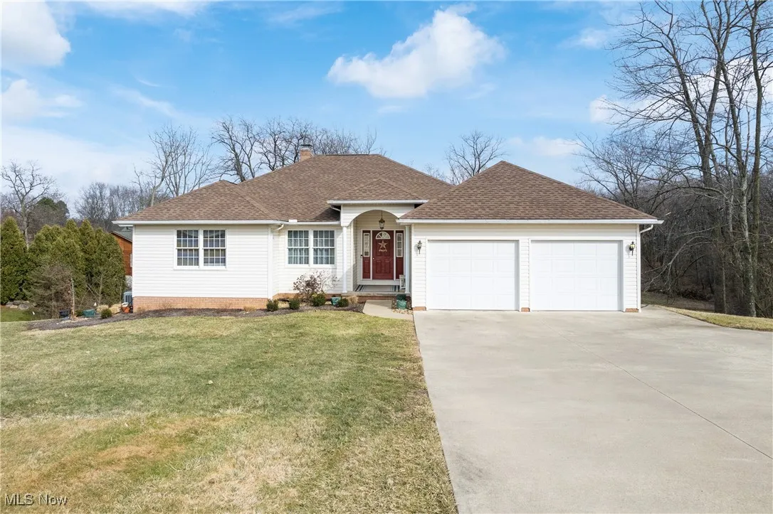Single story home with driveway, a chimney, roof with shingles, an attached garage, and a front lawn