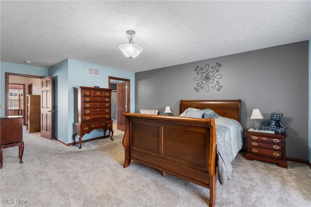 Carpeted bedroom with visible vents, a textured ceiling, and baseboards