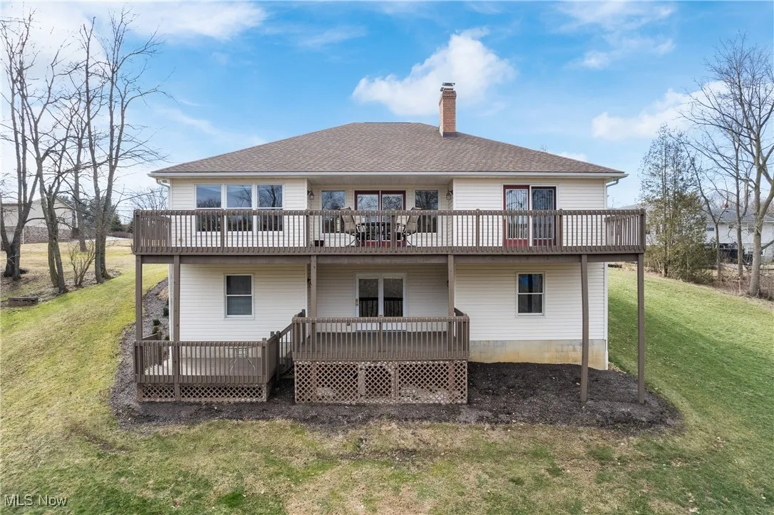 Back of property with a deck, a yard, a chimney, and roof with shingles