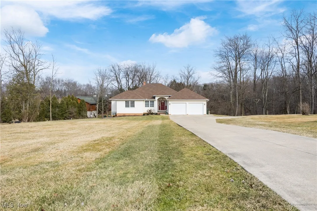 View of front of house featuring a garage, concrete driveway, a front lawn, and a chimney