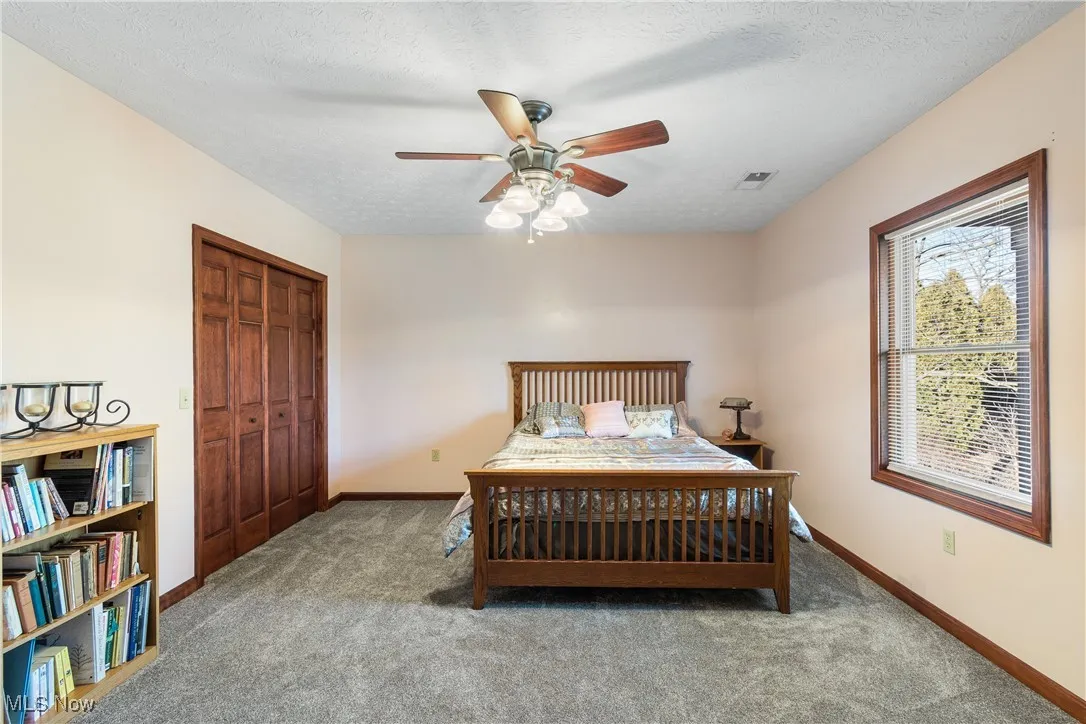 Carpeted bedroom featuring a closet, visible vents, a textured ceiling, and baseboards