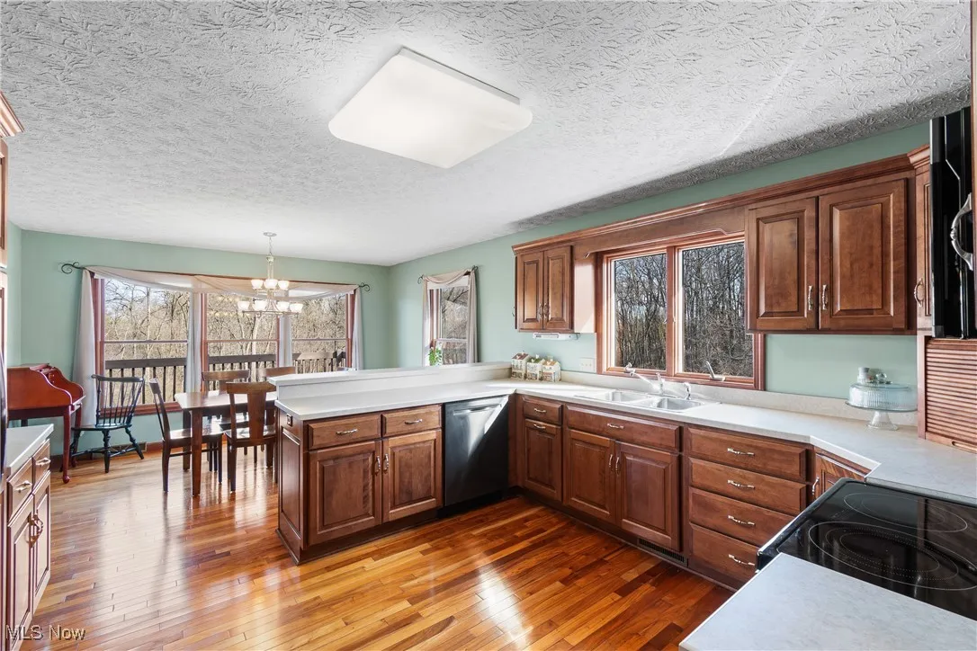 Kitchen with light countertops, a sink, a peninsula, and stainless steel dishwasher