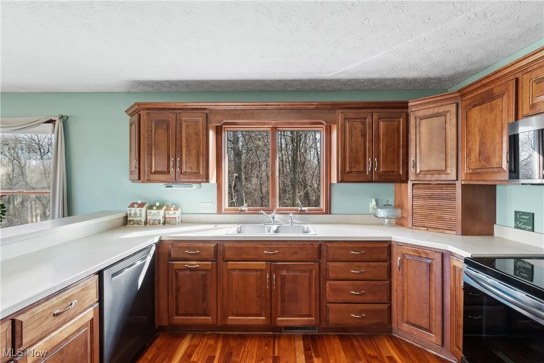 Kitchen featuring stainless steel appliances, dark wood-type flooring, a sink, and light countertops
