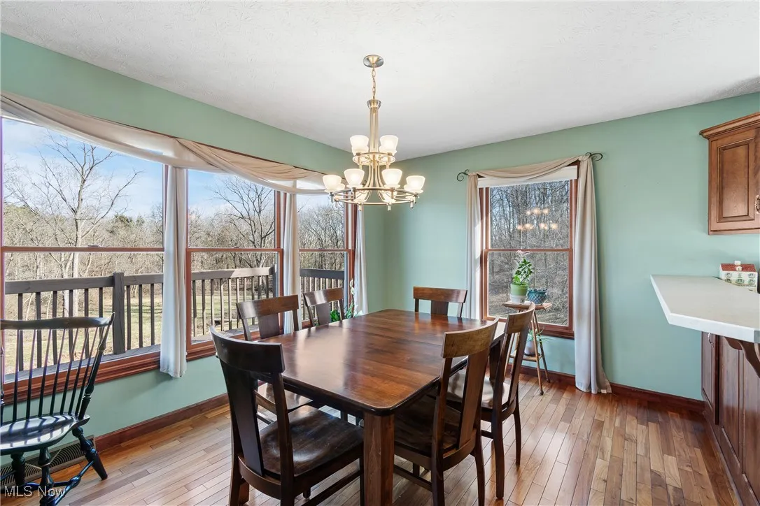 Dining room with a notable chandelier, light wood-style flooring, and baseboards