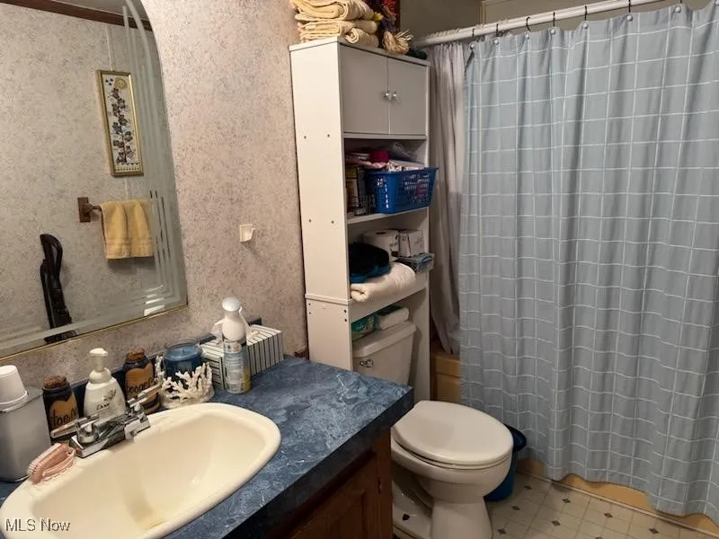 Full bathroom with a shower with shower curtain, vanity, and toilet