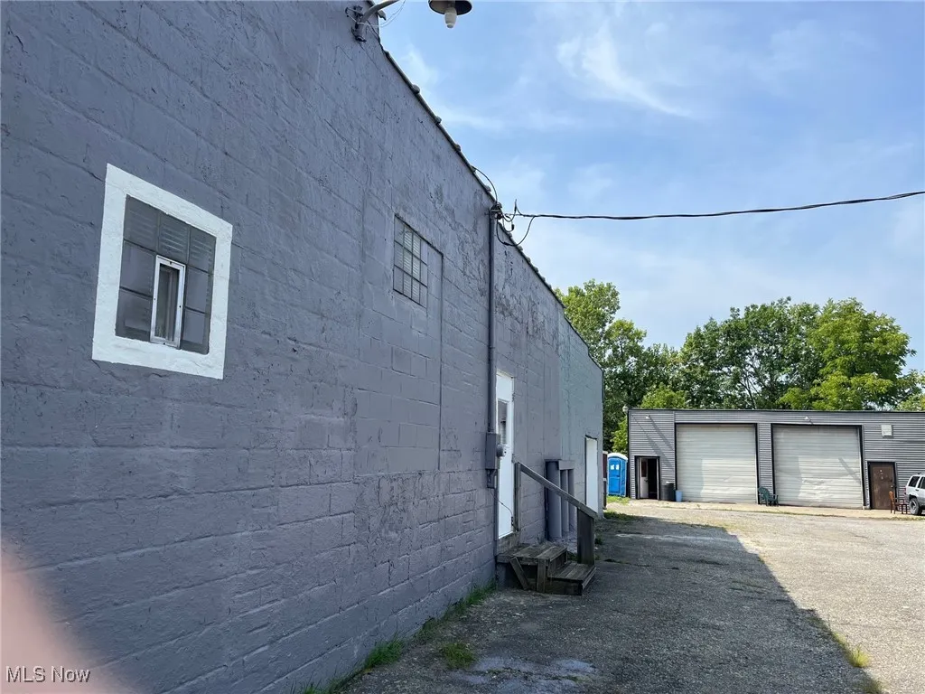 View of side of structure featuring entry steps, concrete block siding, a detached garage, and an outdoor structure
