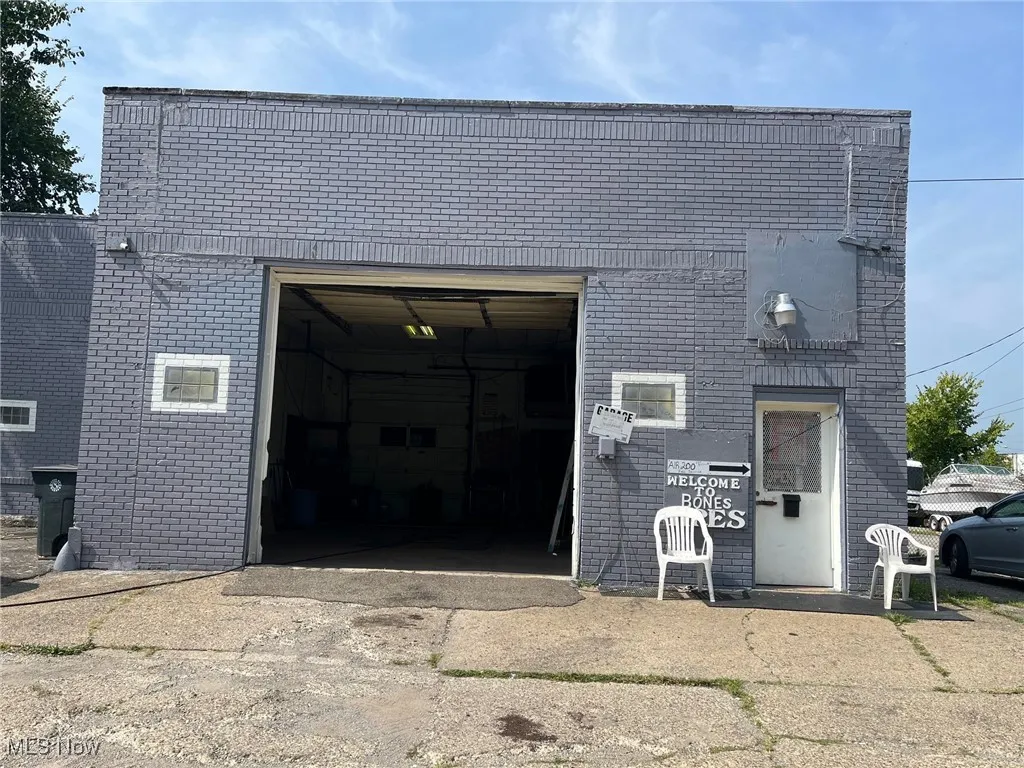 View of front facade with a garage, an outbuilding, and brick siding