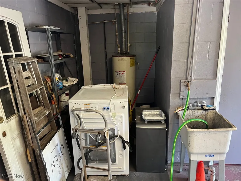 Utility room with washer / dryer, gas water heater, and a sink