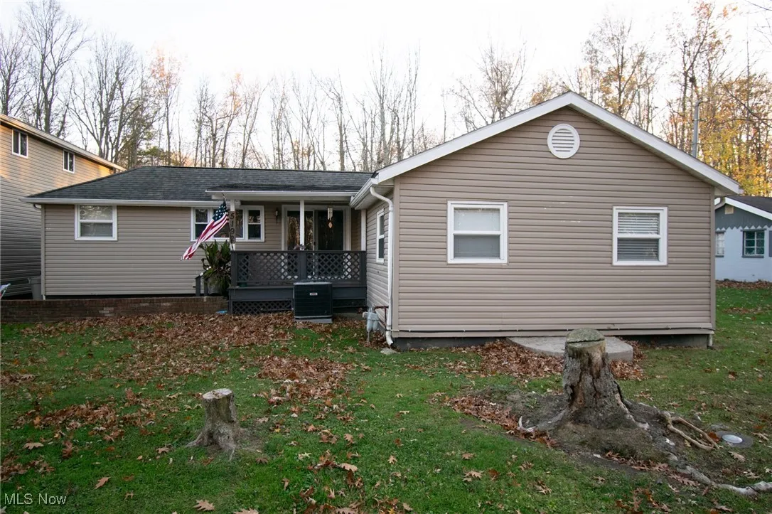 Rear view of house featuring covered porch, a yard, and central air condition unit