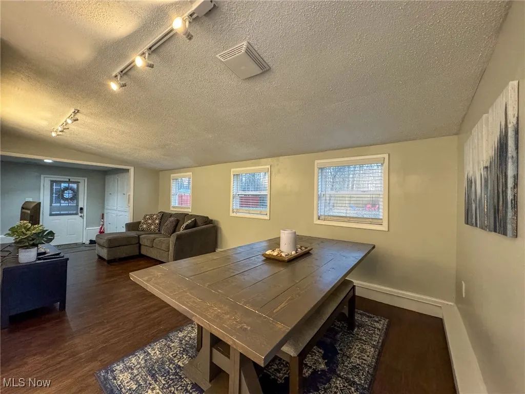 Dining area featuring visible vents, a textured ceiling, baseboards, and wood finished floors