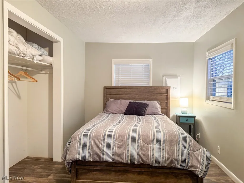 Bedroom featuring a closet, a textured ceiling, baseboards, and wood finished floors