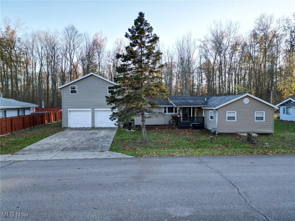 View of front of house with driveway, a front lawn, an attached garage, and fence