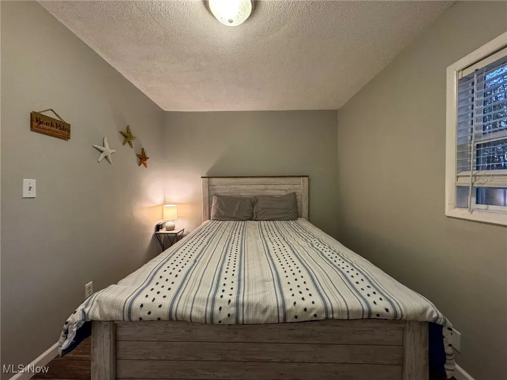 Bedroom featuring a textured ceiling, wood finished floors, and baseboards