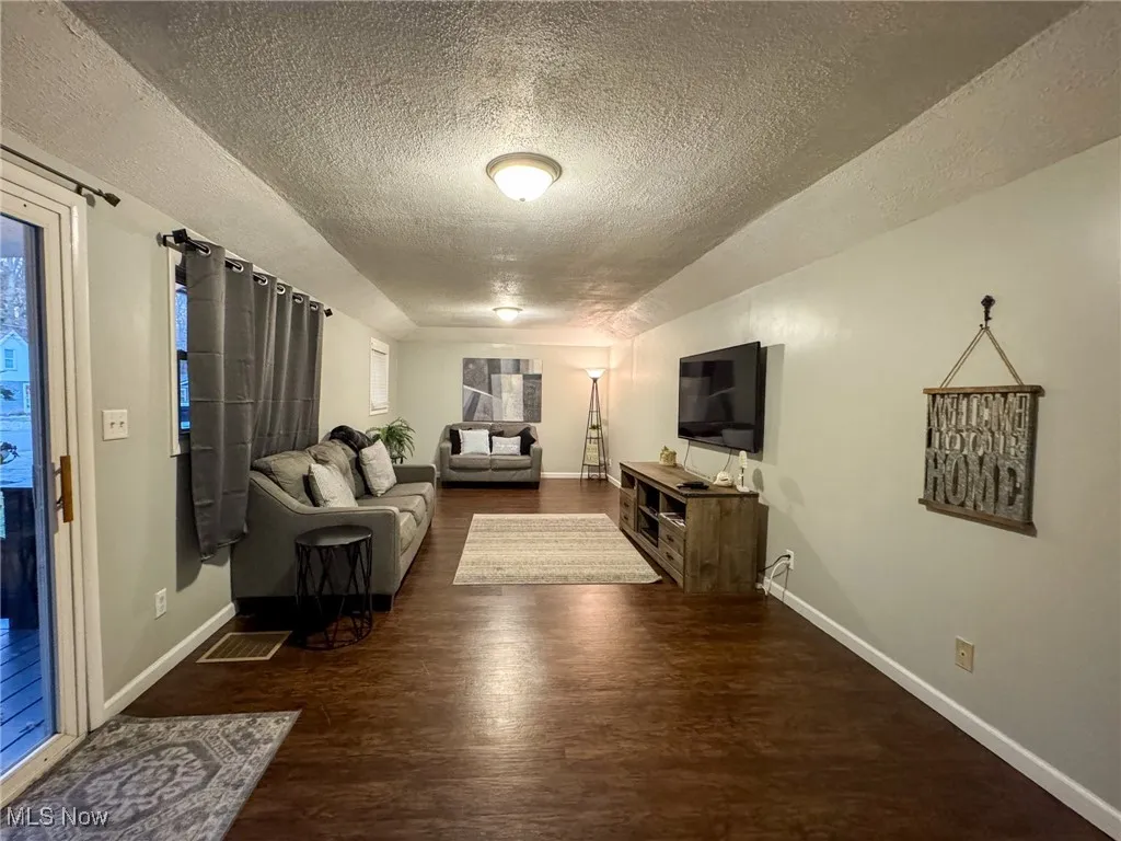 Living area featuring a textured ceiling, wood finished floors, and baseboards