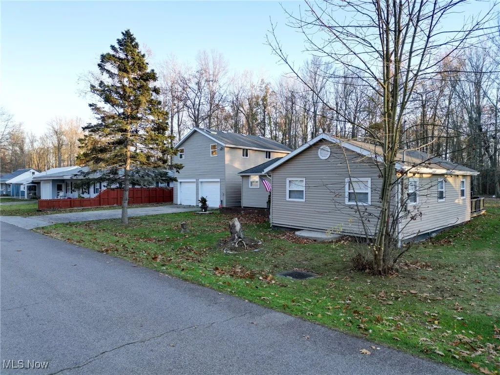 View of side of property with a garage, driveway, fence, and a lawn