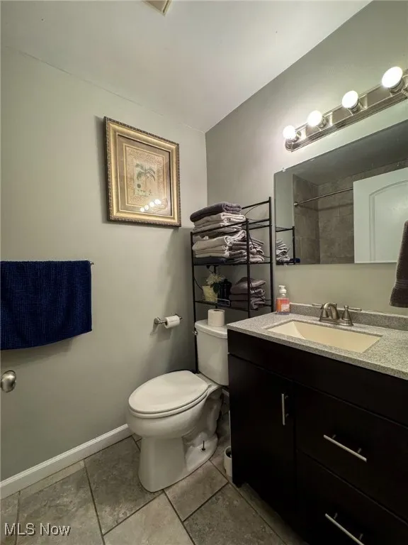 Bathroom featuring toilet, baseboards, a shower, and vanity