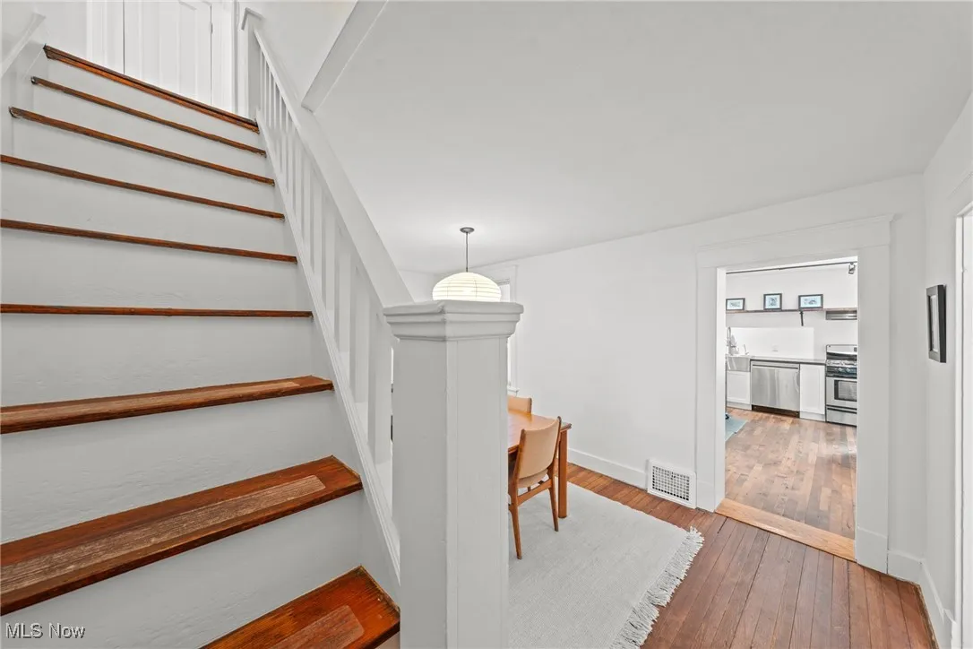 Stairs featuring wood-type flooring, visible vents, and baseboards