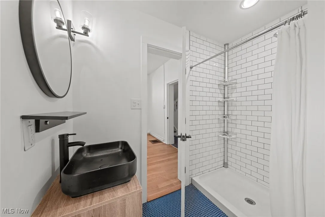 Bathroom with baseboards, visible vents, wood finished floors, a shower stall, and a sink