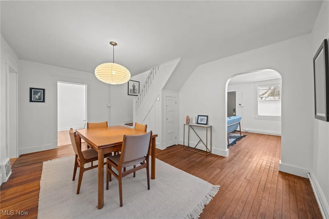 Dining area featuring arched walkways, stairs, hardwood / wood-style flooring, and baseboards