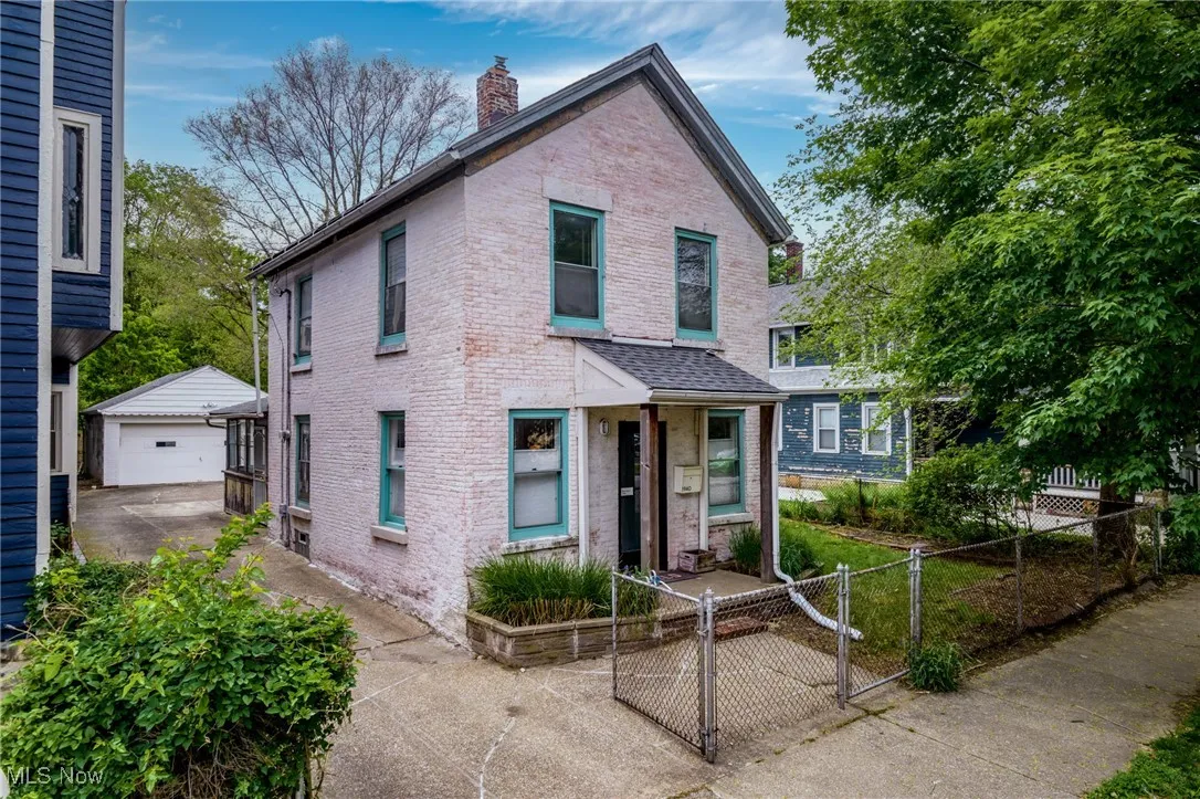 View of front of home featuring brick siding, a fenced front yard, a chimney, an outbuilding, and a detached garage