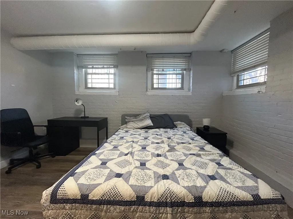 Bedroom featuring wood finished floors and brick wall